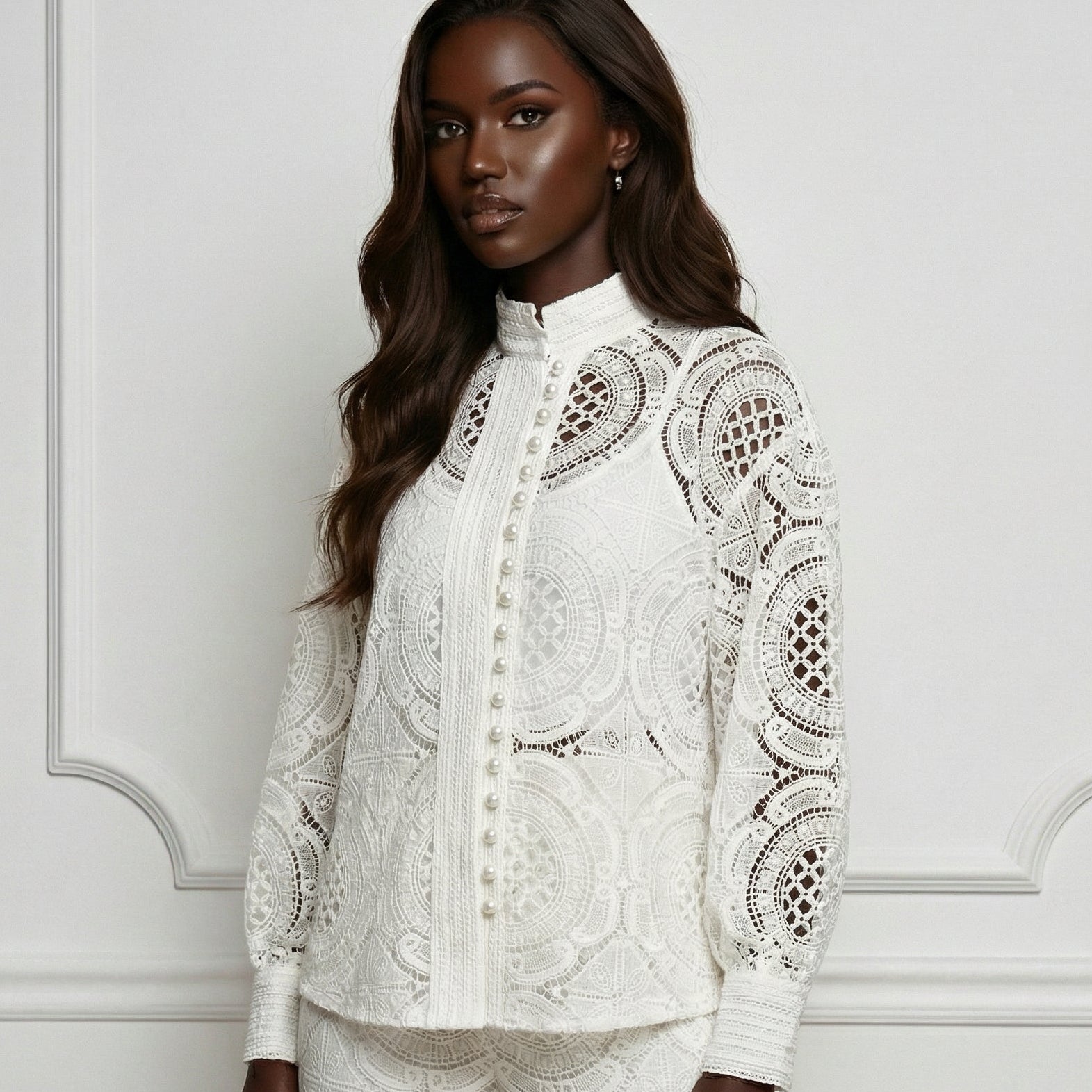 Woman wearing a white lace outfit against a white wall