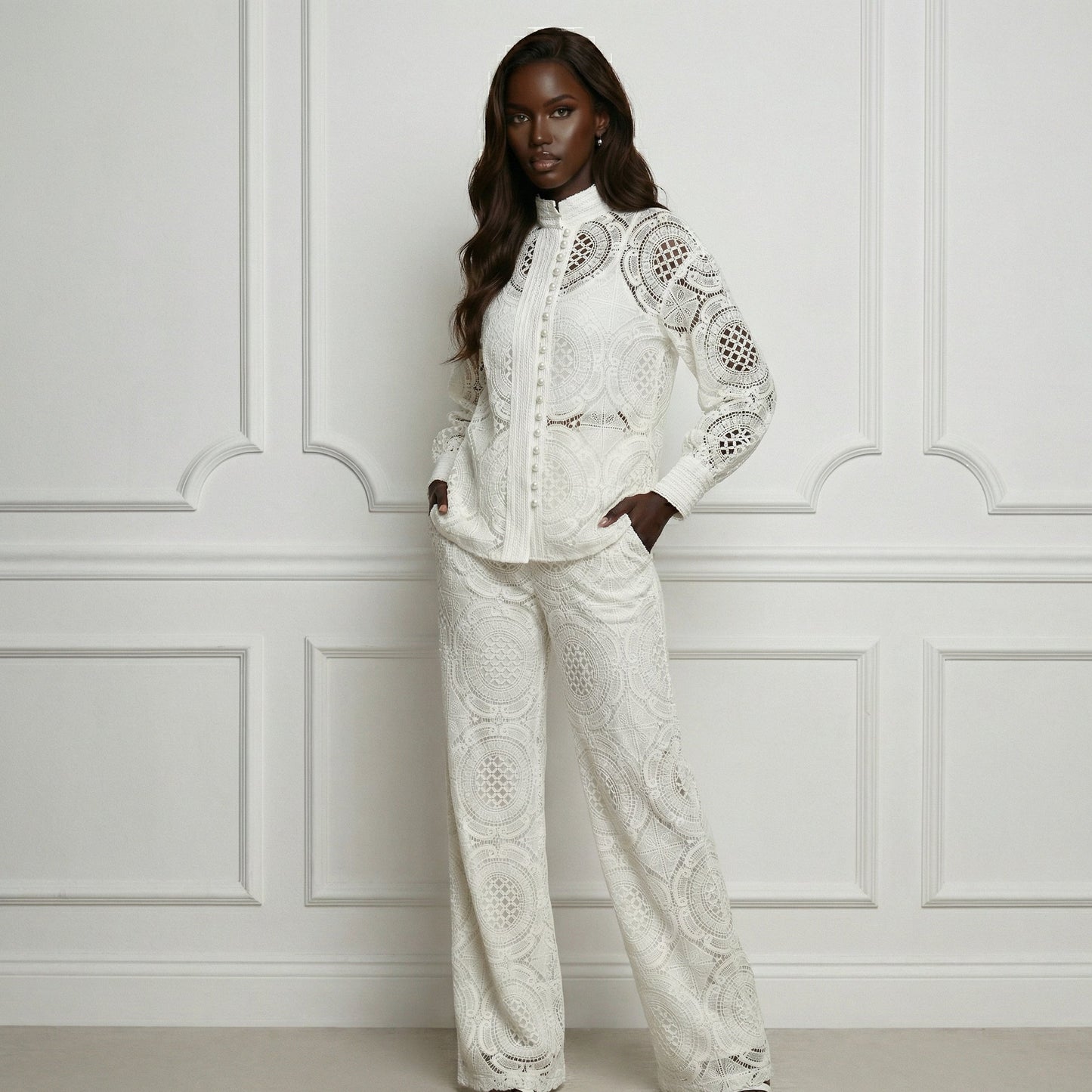 Woman wearing a white lace outfit against a white paneled wall.