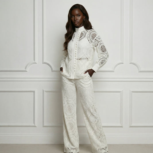 Woman wearing a white lace outfit against a white paneled wall.