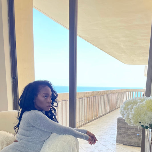 Model seated by ocean view wearing Mock Neck Stretchy Long Sleeve Crop Top